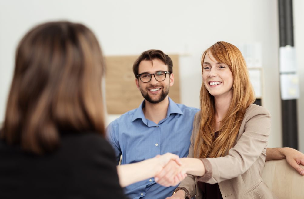 Ein Mann und eine Frau in einem Büro schütteln sich die Hände, was für eine erfolgreiche Zusammenarbeit steht
